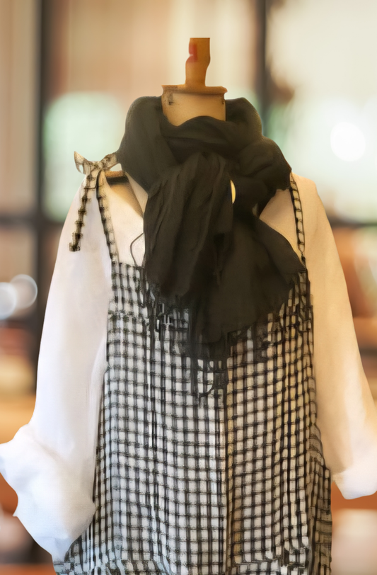 A black limen scarf tied casually around the neck of a store dummy, displaying black and white checked overalls and a white linenshirt.
