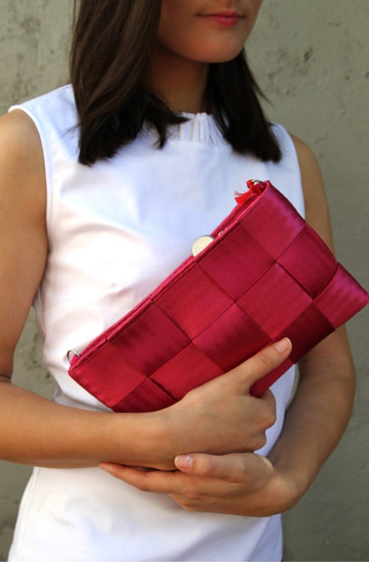 Upcycled car seat belt bag in Berry Crush. A warm pink toned red criss cross pattern with seatbelt texture, and a long over the shoulder style strap.