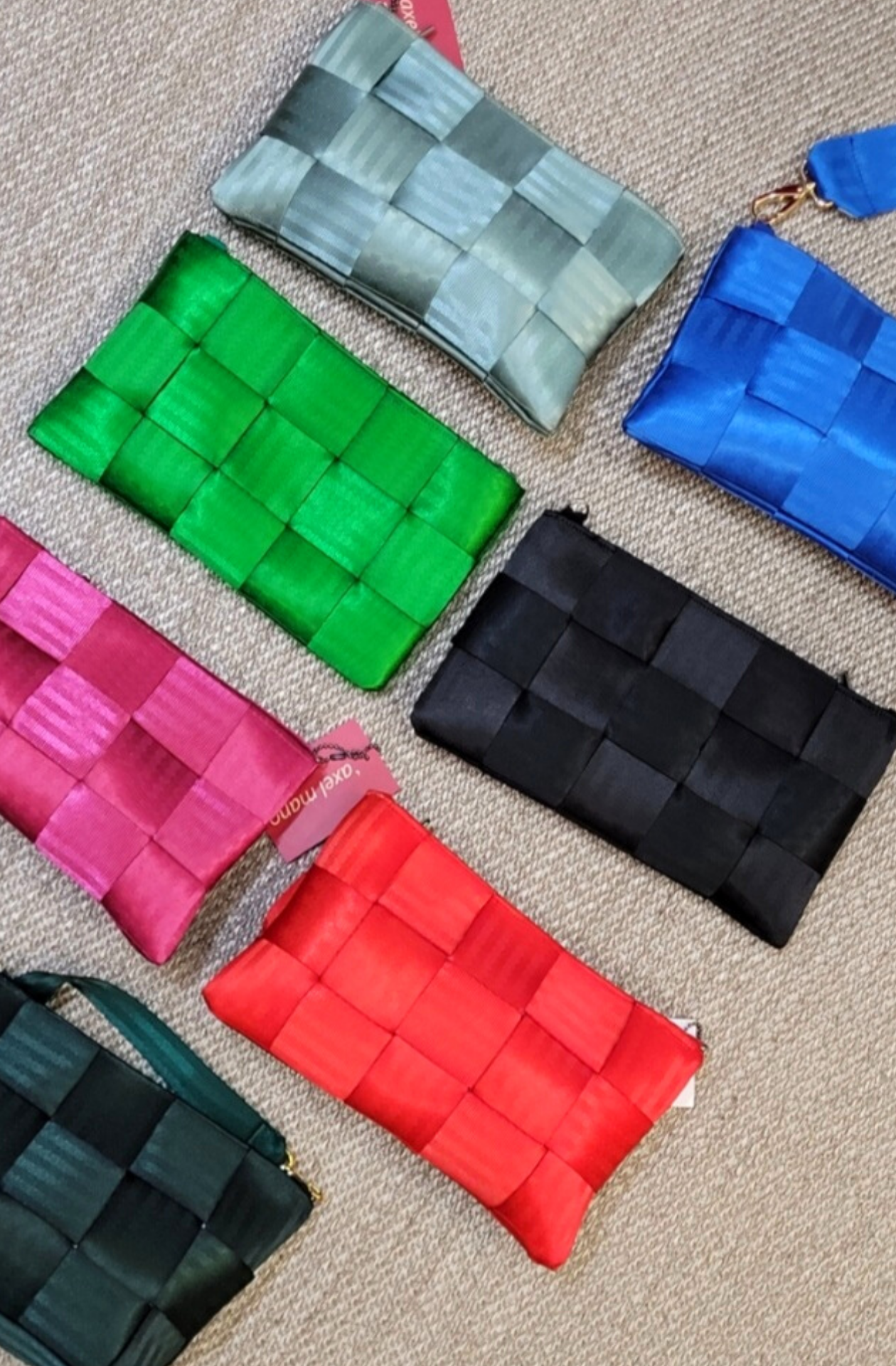Several coloured Axel Mano clutch purses layed out next to eachother, comparing colours