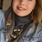 Woman wearing a grey cotton scarf with silver sequin accents and a denim jacket.