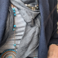 Person wearing a blue jacket with a grey cotton scarf embellished with sequins, wearing turquoise decorative elements.