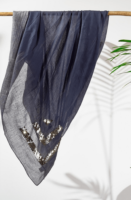 Grey cotton scarf with sequin details draped over a wooden rod on a white background.