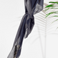 Grey square cotton scarf with sequin details draped over a wooden rod on a white background.