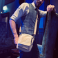 A fashionable young man poses casually in cocktail bar, with a Where The Wilde Things Are sustainable canvas crossbody bag slung over his shouder