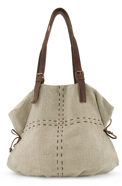 With a large carrying capacity and decorative hand stitching, the shoulder bag has leather side ties to give it an appealing shape and two leather shoukder straps with decorative brass buckles. Its colour is a soft ever so  slightly green neutral called lichen , made from ethically sourced jute