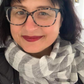 a smiling woman with a dark bobbed haircut wearing glasses and a striped linen scarf in a striped pattern of white and black/blue