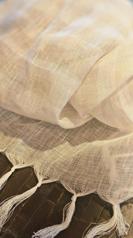 A 100% linen handloomed striped scarf  with a deep tasseled border. the colourway is a natural white with alternating sand  a narural colour with sandorizontal stripes. 