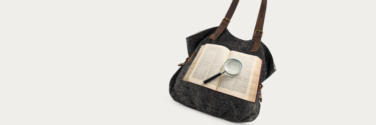 Black jute shoulder bag with an open book and magnifying glass on a light gray background