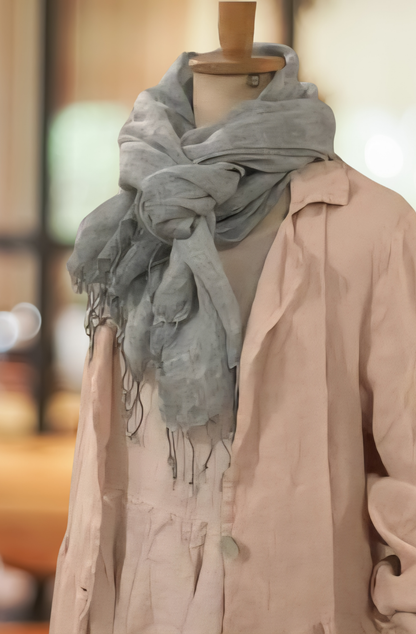 a LIGHT GREY COLOURED LINEN SCARF IS Casually tied at the neck of a store mannequin, dressed in an oyster coloured linen dress and mushroom pink coloured lienen duster.