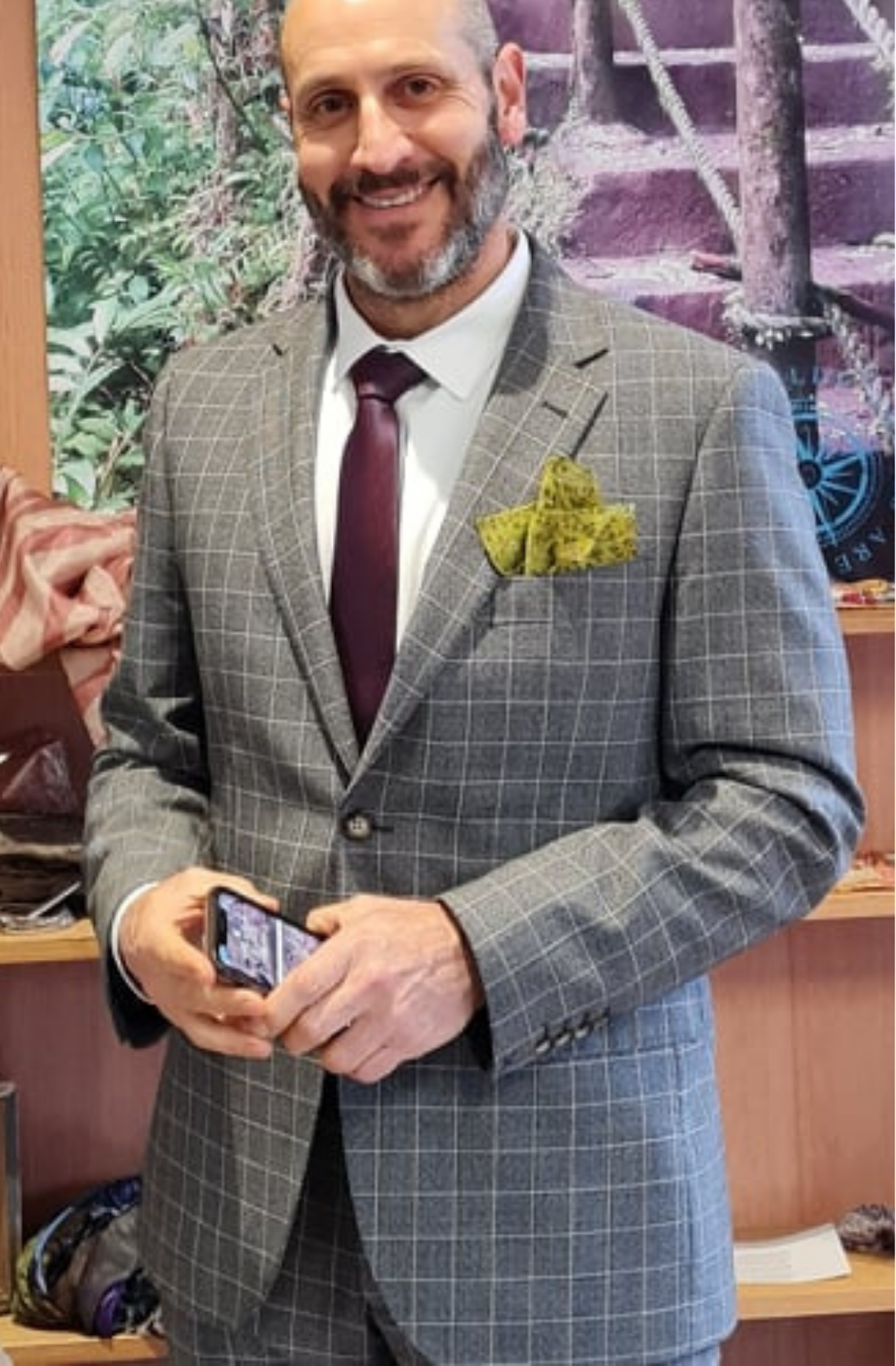 Man in a grey suit with a deep red tie and an olive green floral patterned pocket square