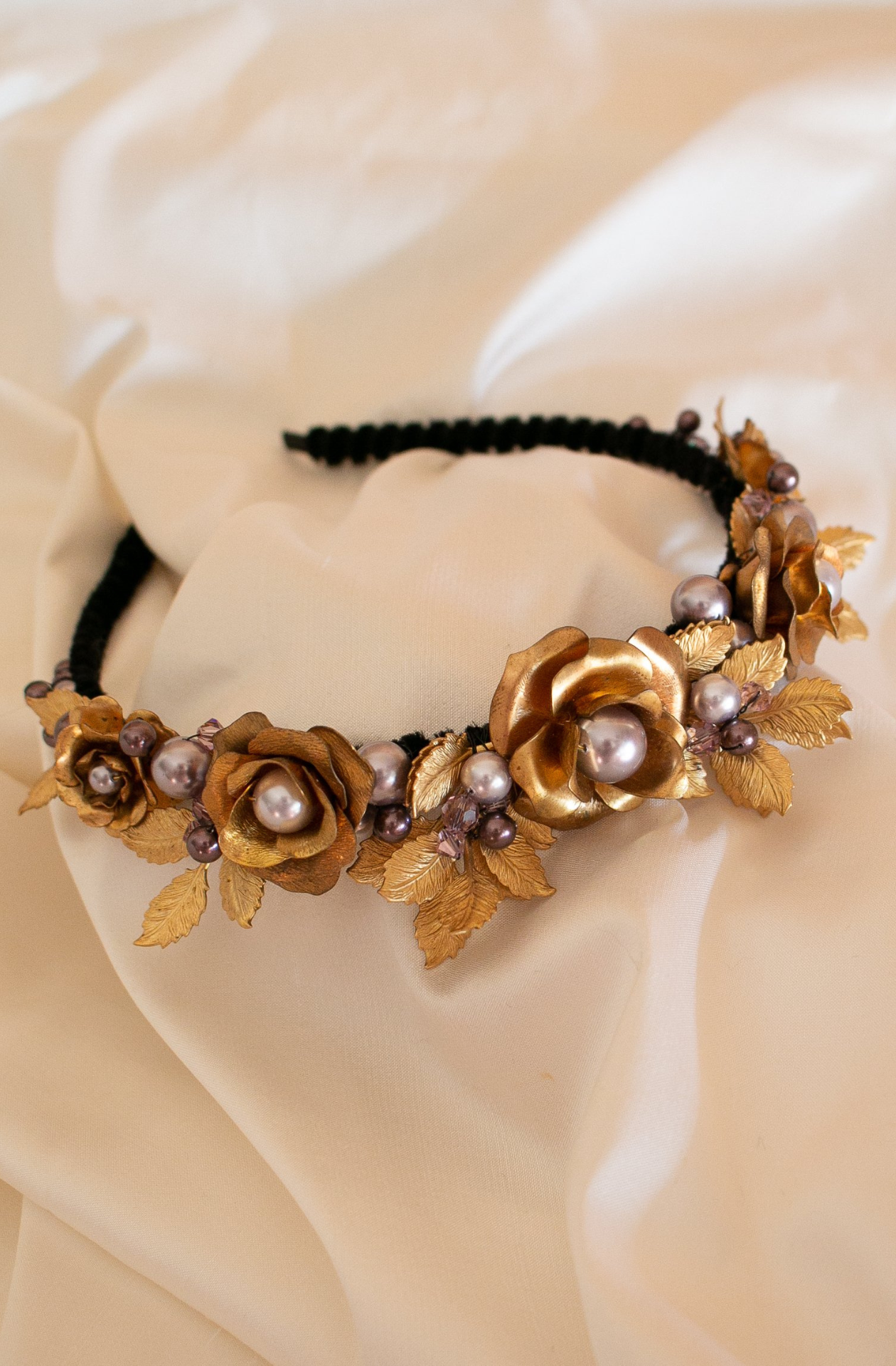 A narrow black velvet covered headband featuring vintage golden brass roses and leaves amongst mixed shades of lavender Swarovski pearls 