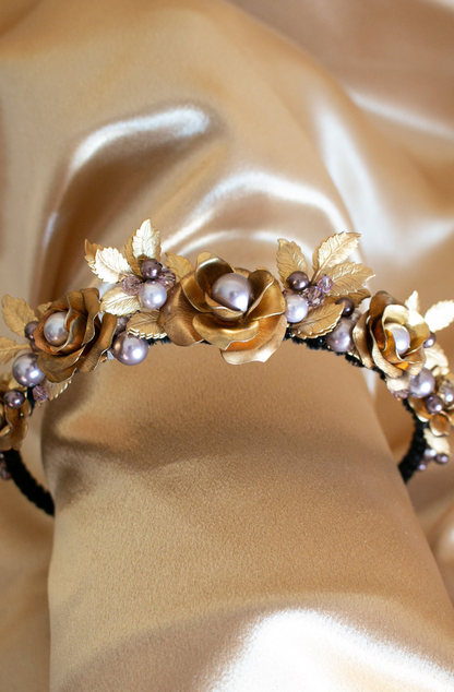 A narrow black velvet covered headband featuring vintage golden brass roses and leaves amongst mixed shades of lavender Swarovski pearls 