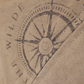 a closeup of the Where The Wilde Things are Compass logo stencilled on  khaki coloured 100% cotton canvas 