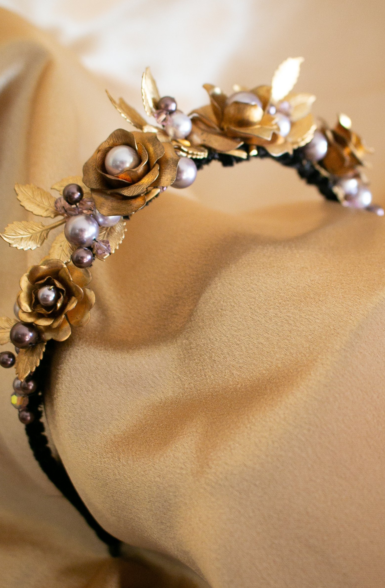 A corded black headband featuring golden roses and leaves sat atop, mixed in with swarovski crystals and pearls of different shades