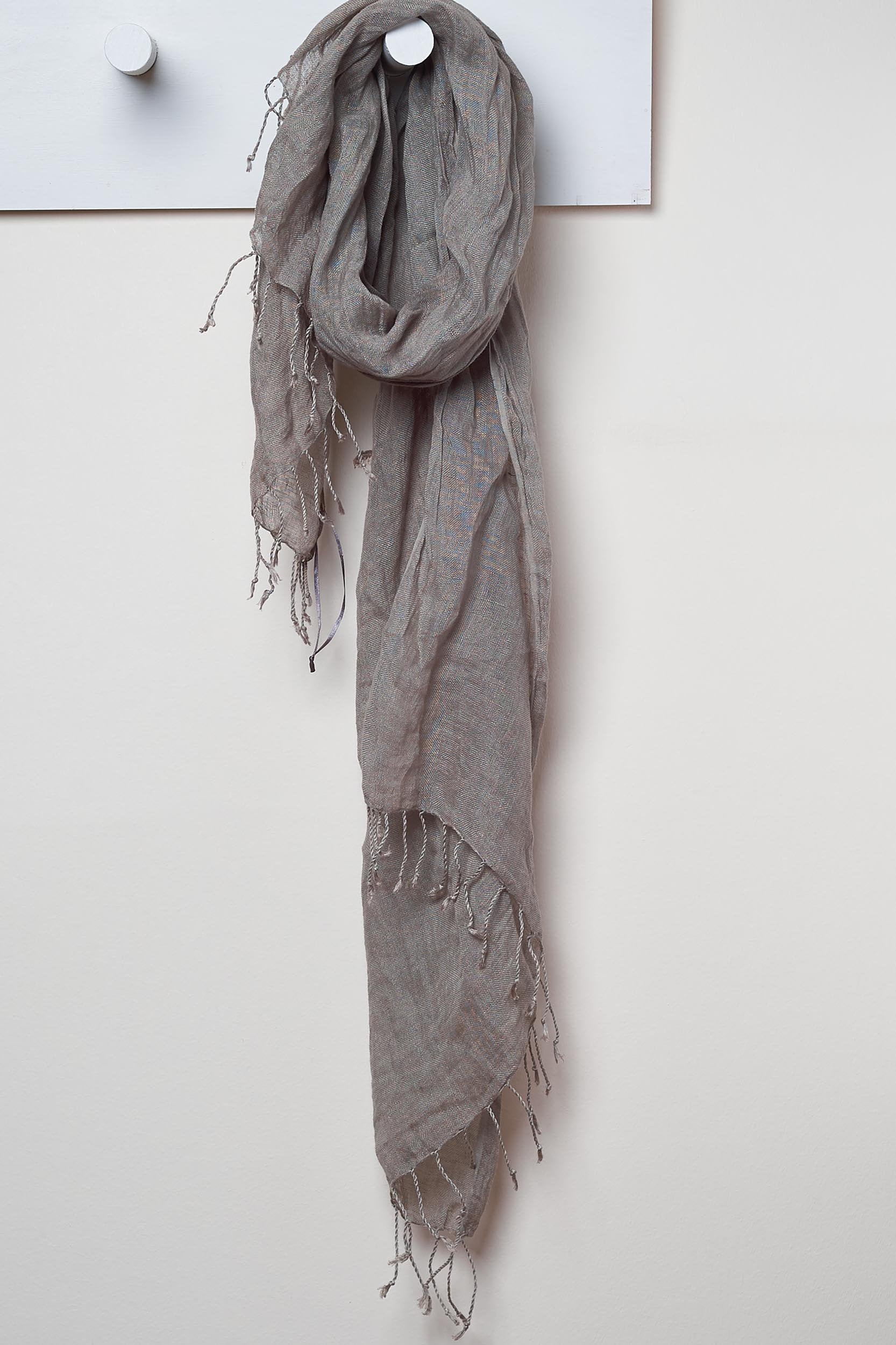 Jungle Moss linen Scarf. looped around a hook detailing the linen texture and thin tassels tied at the short edges of the scarf.
