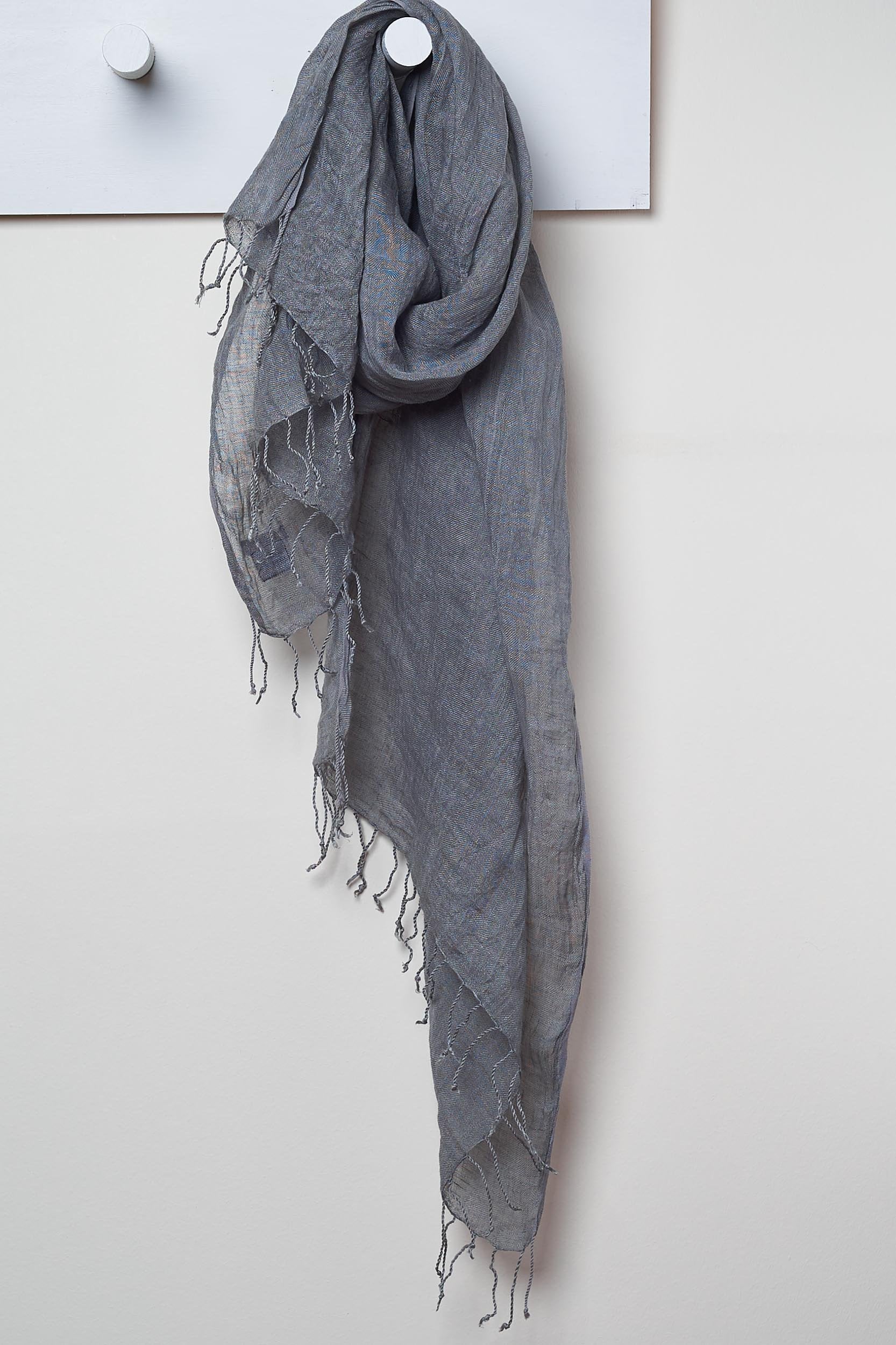 3 Visits To Cairo pure linen scarf in Charcoal. looped around a hook detailing the linen texture and thin tassels tied at the short edges of the scarf.