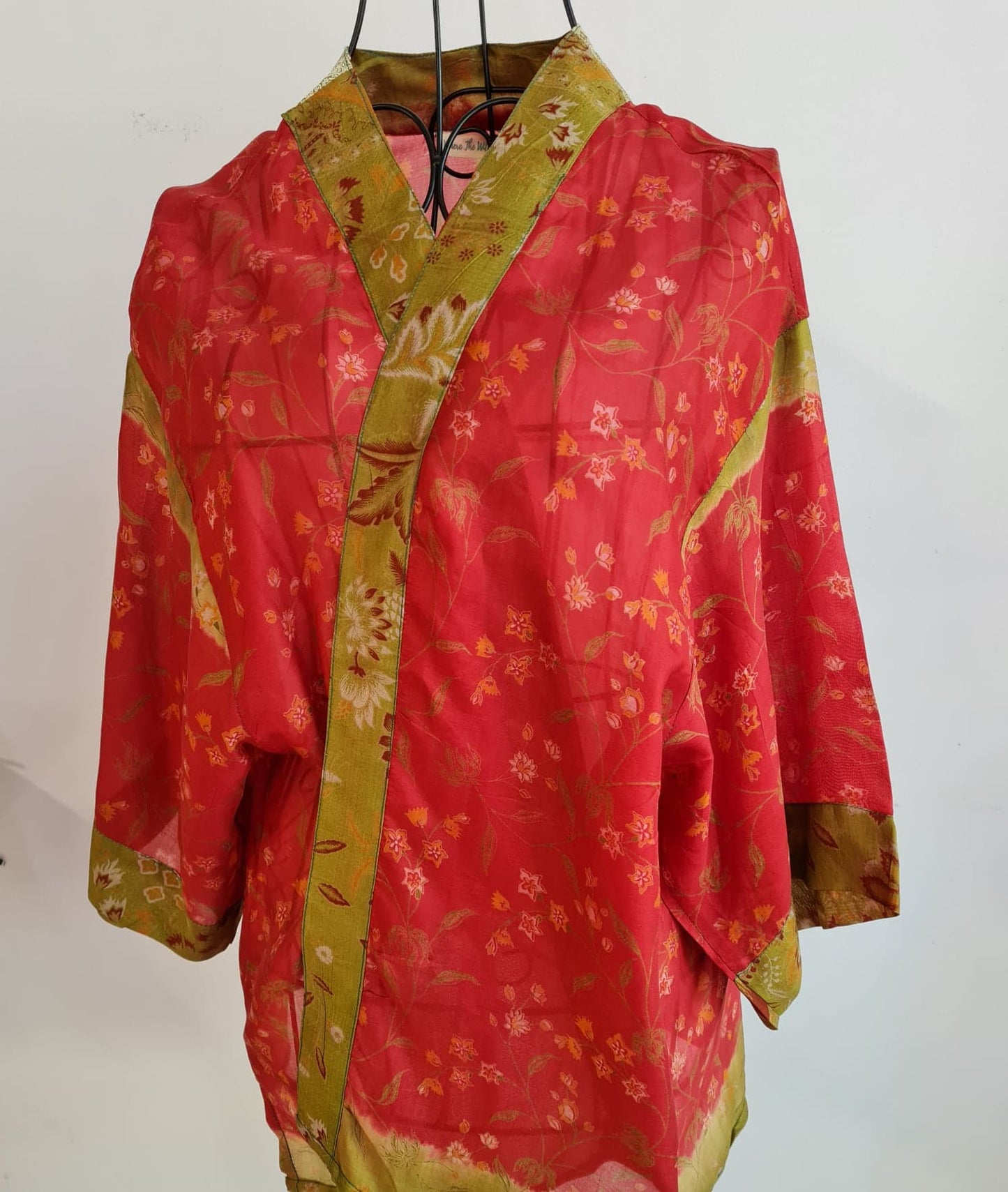 a red muse jacket with a very faint pink and orange floral pattern. A golden and red trim surrounds all the edges. 