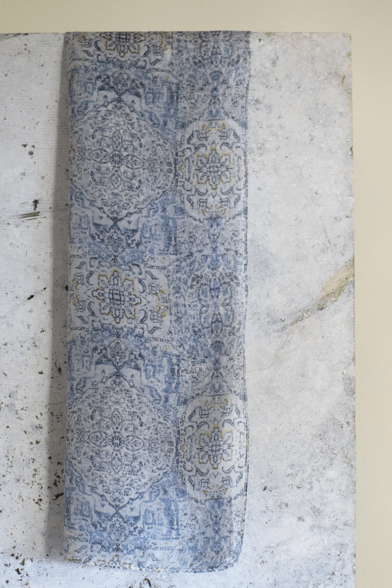 the blue mist scarf hanging on a slab of marble emphasising the deep blue tones