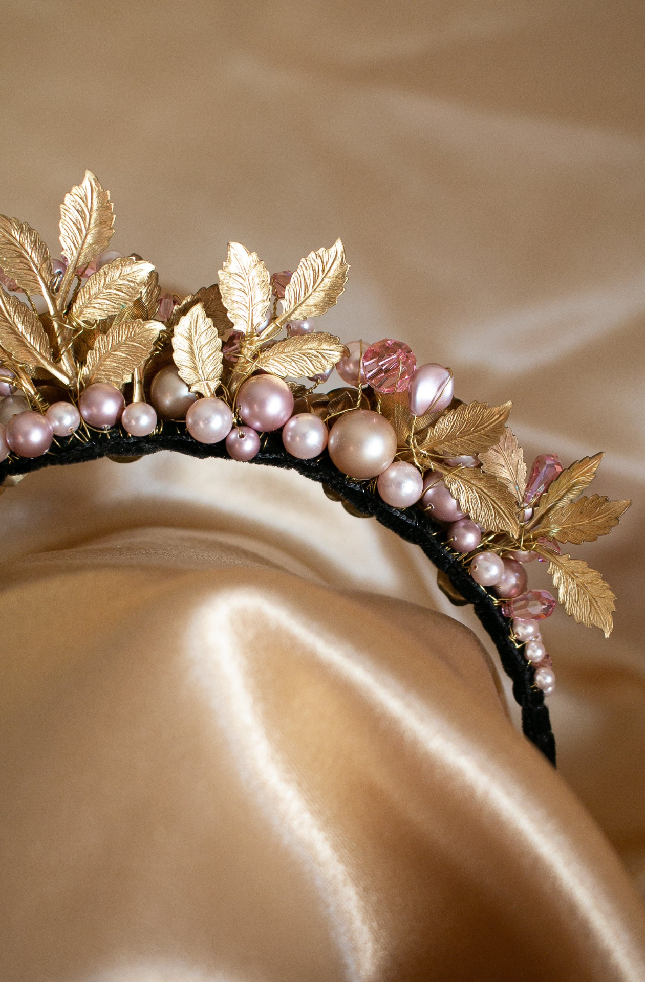 Rear view of a black, velvet covered, narrow headband with a large arrangement of vintage brass flowers, leaves, Swarosvki pearls and crystals in shades of delicate, soft pinks. Handmade in Melbourne