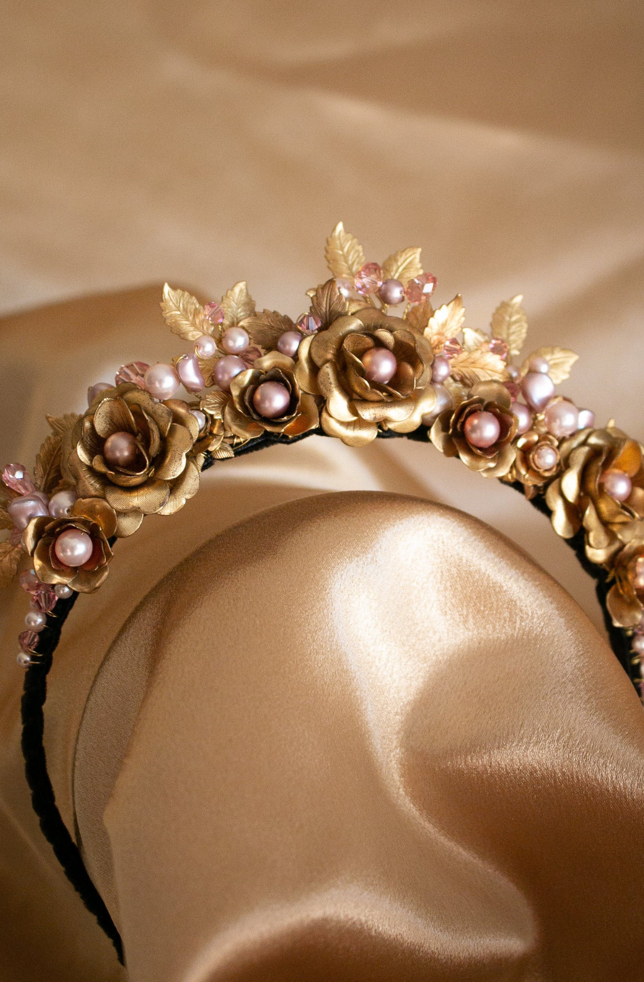 A black, velvet covered, narrow headband with a large arrangement of vintage brass flowers, leaves, Swarosvki pearls and crystals in shades of delicate, soft pinks. Handmade in Melbourne
