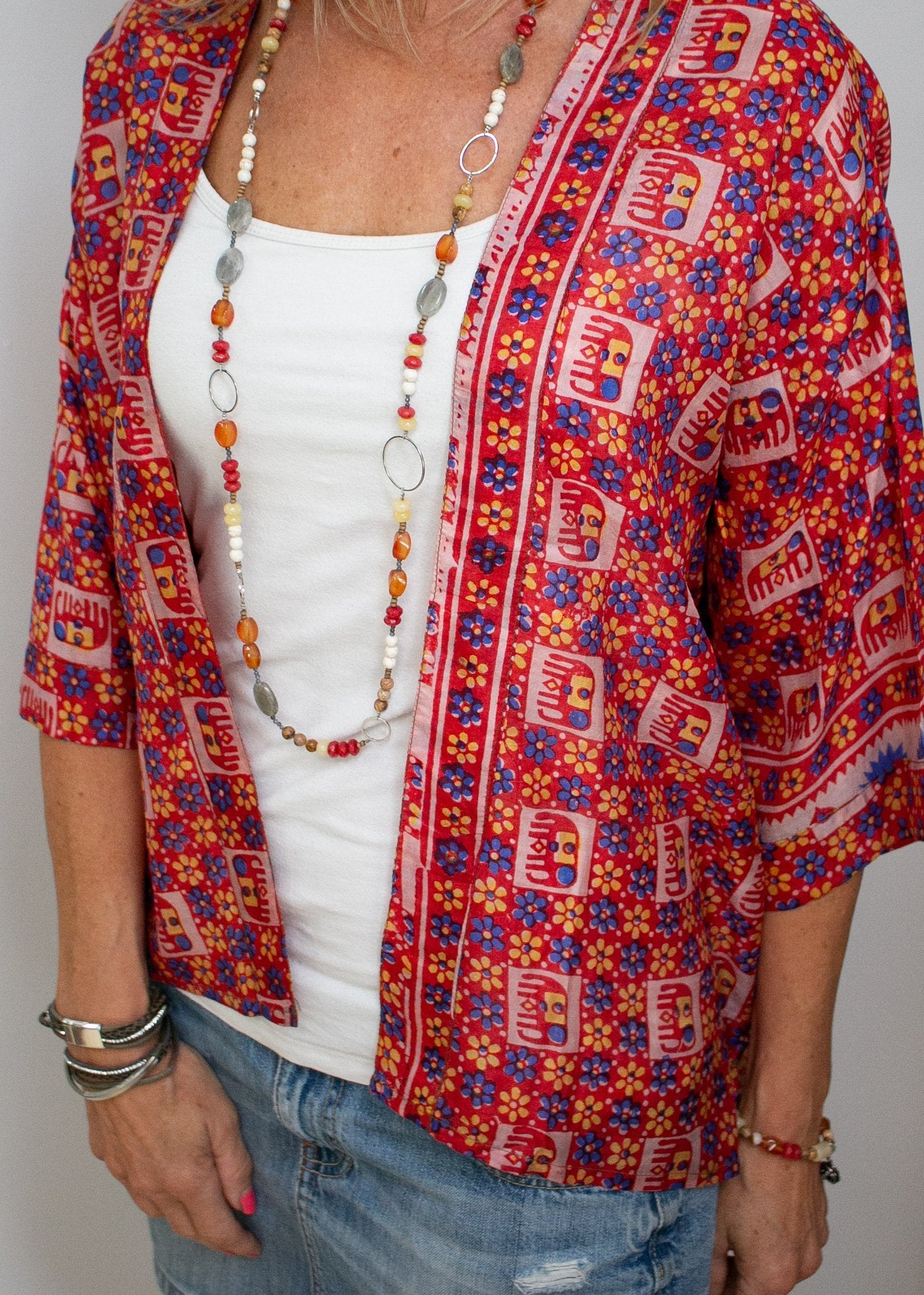a red jacket with yellow and blue simple flowers, as well as repeating simple elephant prints in red yellow and blue. 