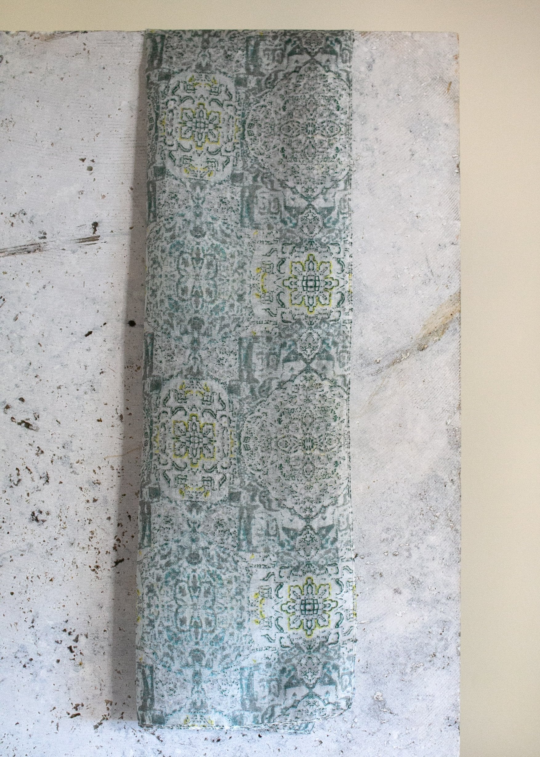 the pistachio scarf hanging on a slab of marble emphasising the deep grey-green tones